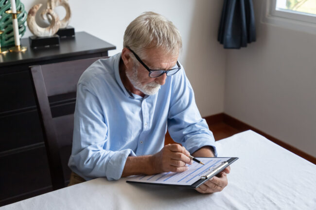 Senior,Old,Man,Elderly,Reading,And,Examining,Reverse,Mortgage,Application
