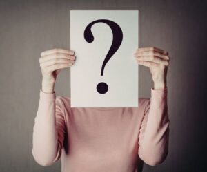 person holding up a paper with a question mark on it