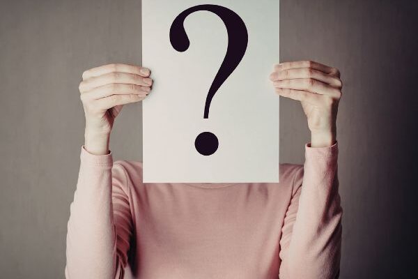 person holding up a paper with a question mark on it