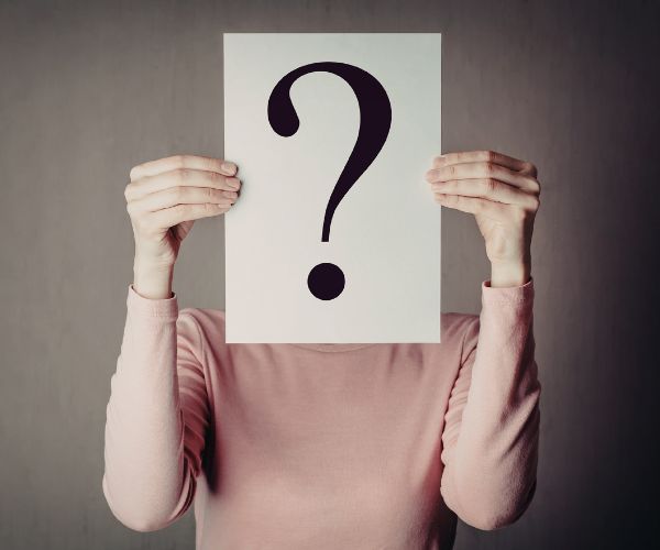 person holding up a paper with a question mark on it