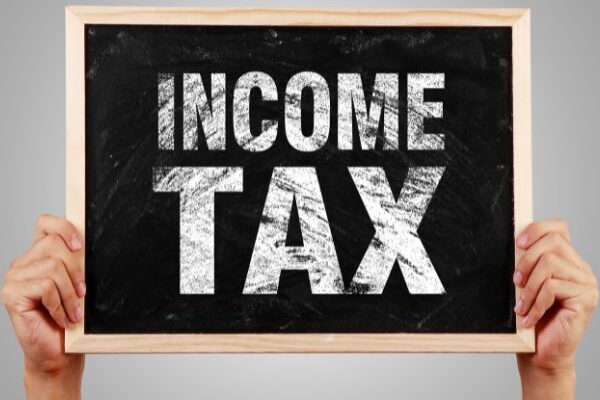 person holding up sign that says income tax